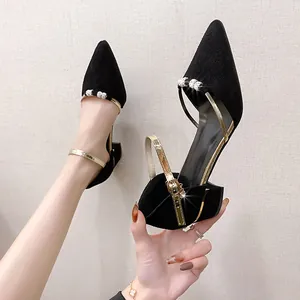 Close-up of black pointed-toe chunky heel shoe with rhinestone details and gold strap