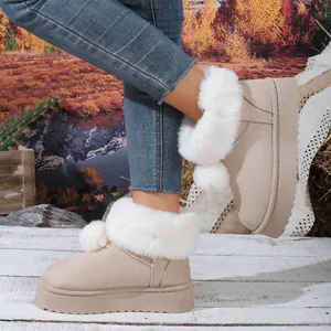 Primer plano de botas de nieve con plataforma beige, piel sintética blanca y pompones