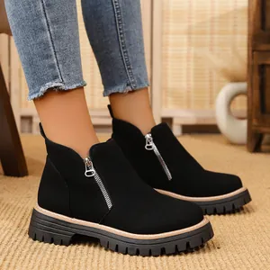 Close-up of black suede ankle boots featuring silver side zippers and durable thick soles