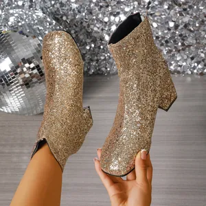 Primer plano de botines de lentejuelas doradas elegantes con tacones altos y gruesos.