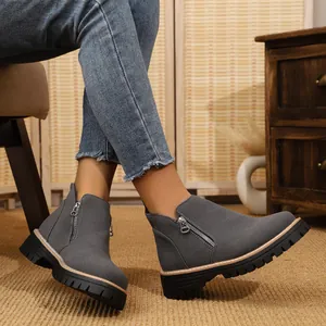 Detail shot of grey suede-like ankle boots with side zipper and chunky sole on model.