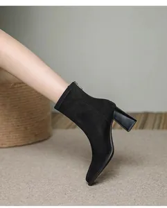 Dettaglio laterale di eleganti stivaletti da donna in camoscio nero con tacco largo chic