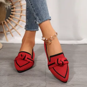 Primer plano de manoletinas de punto rojo con punta fina y lazo negro decorativo