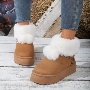 Detalle de botas de nieve marrones para mujer con adorno de piel sintética y pompones.