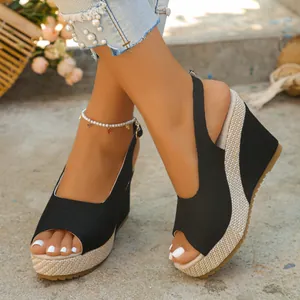 Elegant close-up shot of black peep-toe wedge sandals featuring a woven platform heel