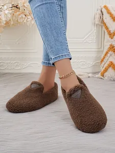 Detailansicht brauner flacher Damen-Plüschschuhe mit weicher Sohle an Füßen