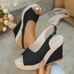 Detailed view of women's black peep-toe wedge sandals with woven jute platform strap