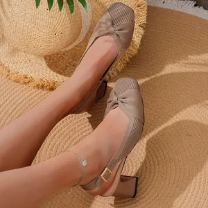 Vista dettagliata di scarpe in maglia beige con fiocco su un tappeto di paglia naturale