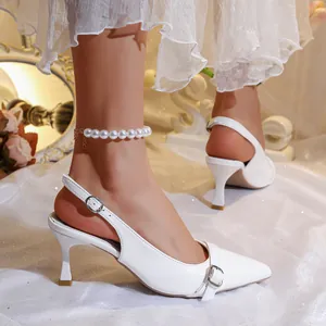 Close-up of white patent leather slingback high heels with elegant pointed toe design.