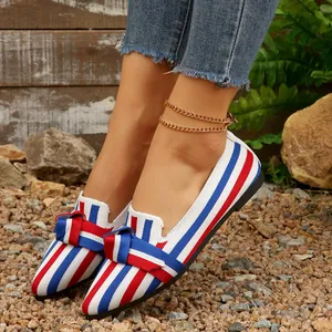 Dettaglio di eleganti ballerine a righe rosse bianche e blu con decorazione a fiocco