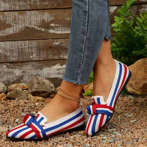 Dettaglio scarpe piatte a punta da donna con strisce rosse bianche e blu e fiocco decor.