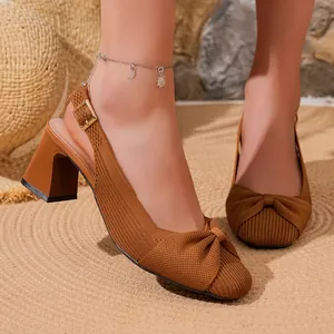 Primo piano di scarpe marroni in maglia con dettaglio a nodo elegante e tacco a blocco.