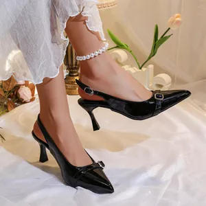 Elegant black patent leather slingback heels with buckle detail worn by model in studio.