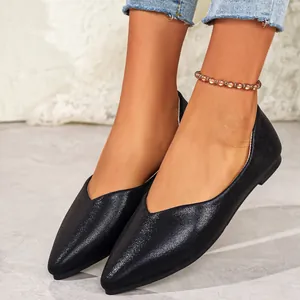 Close-up of elegant black shimmering pointed-toe flats with V-cut design on model feet