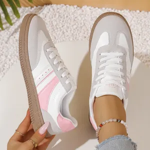 Close-up view of retro women's GAT sneakers featuring pink stripes and white leather