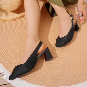 Dettaglio ravvicinato di décolleté slingback nere in maglia con elegante nodo frontale