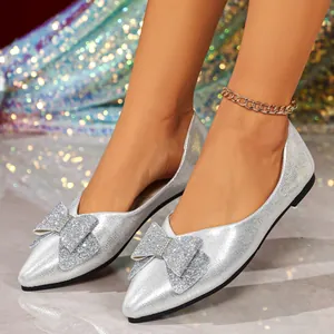 Elegant silver glitter flat shoes featuring a pointed toe and large rhinestone bow detail