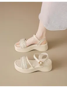 Primer plano de sandalias beige con plataforma, correas trenzadas y brillantes.