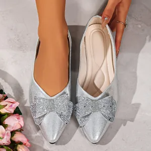 Detail shot of silver pointed-toe flats featuring a sparkling rhinestone bow decoration