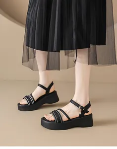 Detalle de sandalias negras de plataforma con tiras de pedrería y colgante estrella.