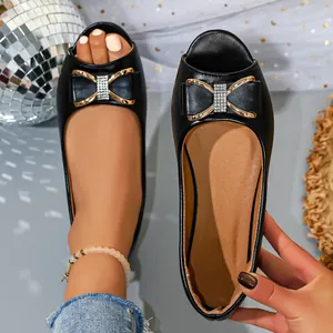 Close-up of black flat peep-toe sandals featuring elegant rhinestone-studded bow details