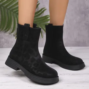 Close-up of stylish black leopard print ankle boots worn with round toe and back zipper