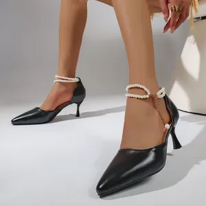 Elegant black pointed-toe high heels with decorative pearl ankle chains detail view.