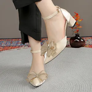 Detalle de zapatos de salón de raso champán con tacón bloque, lazo y tira al tobillo