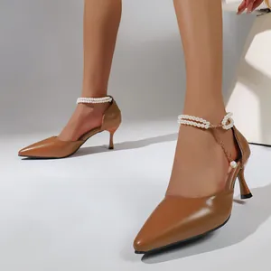 Detail view of brown pointed-toe high heels with elegant pearl chain ankle strap detail.
