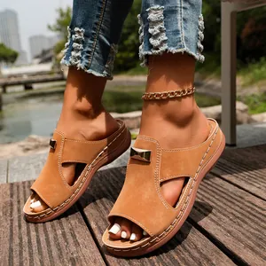 Vue détaillée de sandales compensées marron avec accents métalliques sur une terrasse.