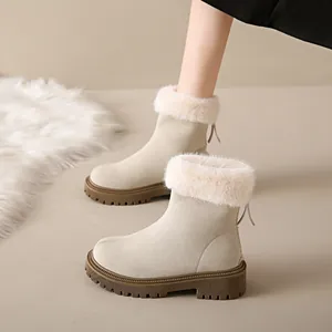 Gros plan de bottes de neige en daim beige avec col en fourrure et semelle épaisse