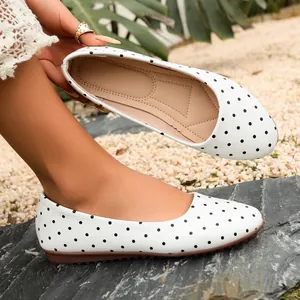 Vista dettagliata di scarpe basse retrò bianche a pois neri con suola marrone morbida