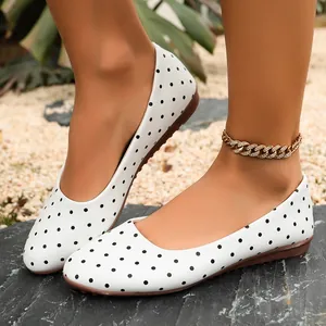 Vista dettagliata di eleganti ballerine bianche da donna a pois neri indossate all'aperto