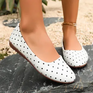 Primo piano di ballerine a pois bianchi con punta tonda e suola morbida marrone