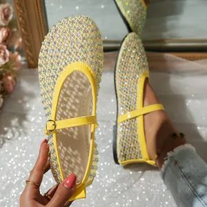 Detalle de sandalias planas Mary Jane de malla amarilla con adornos de strass brillantes.