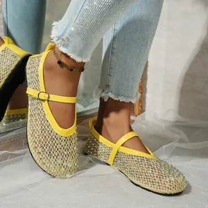 Detalle de sandalias Mary Jane amarillas de malla con pedrería brillante en los pies.