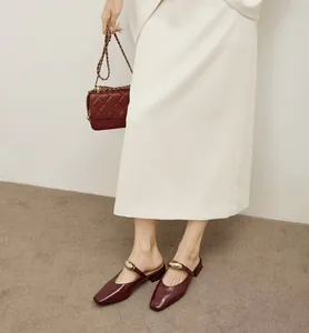 Elegante weinrote Lackleder-Mules mit quadratischer Zehenpartie und Goldverzierung.