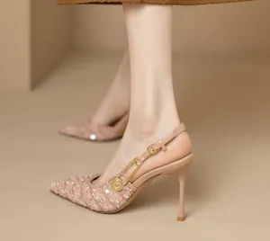 Detailansicht der spitzen Slingback-Pumps mit goldener Nadel und Logo-Verzierung