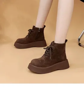 Detailed view of women's brown suede platform boots worn with neutral studio background.