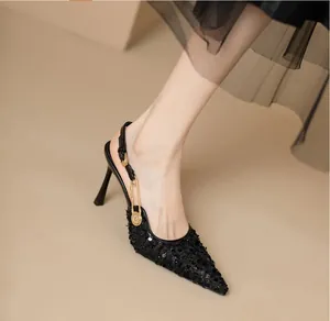 Detailaufnahme schwarzer Pailletten-Slingback-Pumps mit goldener Schmucknadel