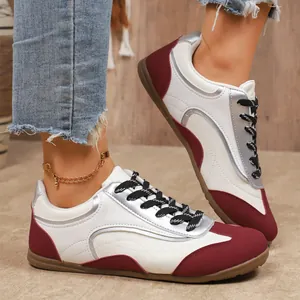Détail de vue latérale de baskets élégantes en cuir blanc, argent et bordeaux chic.