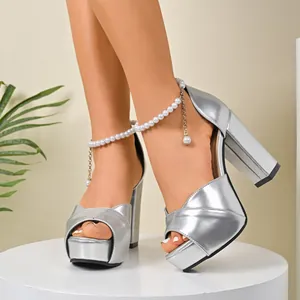 Close-up of silver platform sandals with chunky heels and elegant pearl ankle straps.