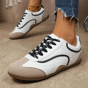 Détail des baskets plates blanches et beiges pour femmes avec lacets noirs style vintage.