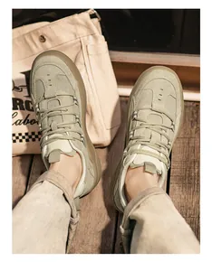 Top view of khaki retro German army trainers worn on a wooden deck lifestyle background.