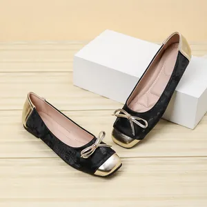 Close-up of black velvet square toe ballet flats with gold bow and metallic accents