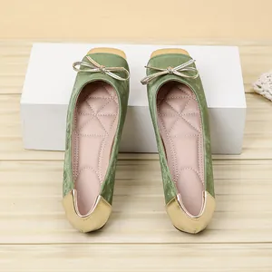 Close-up detail of elegant green ballet flats featuring gold toe cap and bow accent
