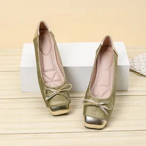 Close-up of elegant green ballet flats with gold metallic square toe and bow
