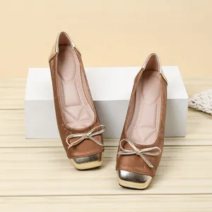 Close-up detail of brown velvet ballet flats featuring a gold square toe and bow.