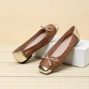 Detailed view of brown suede ballet flats with metallic gold toe and bow decoration