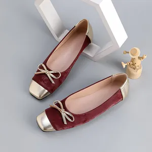 Detailed view of burgundy velvet square-toe ballet flats with metallic gold bow.
